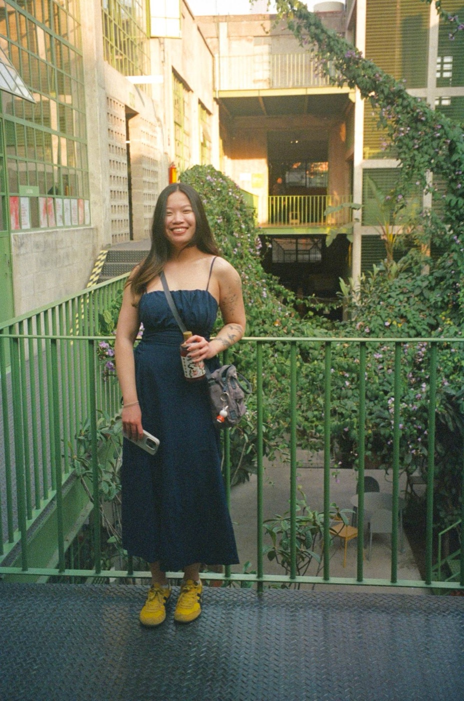 Selina Li standing on a green balcony surrounded by flowering vines